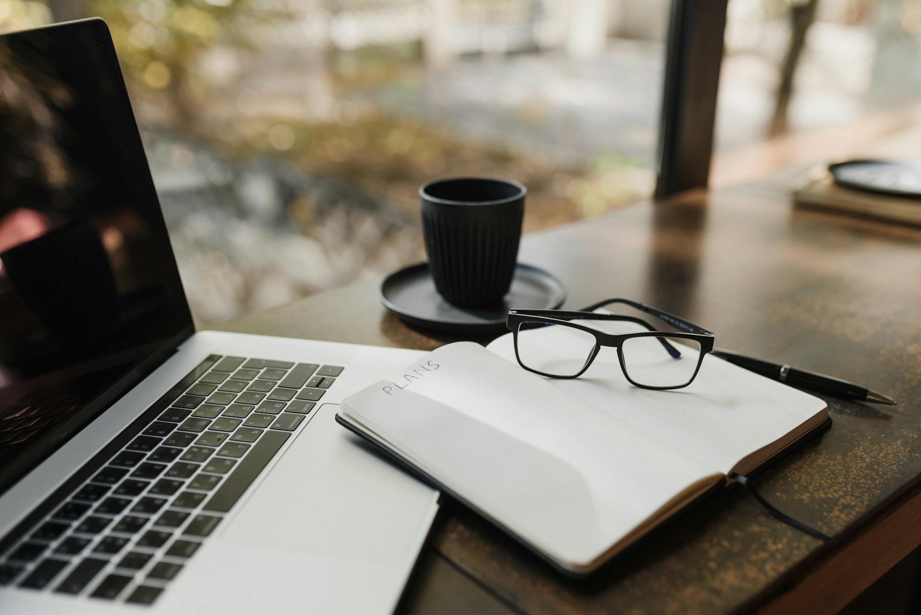 Macbook Pro à Côté De Lunettes Encadrées Noires Sur Une Table En Bois Marron